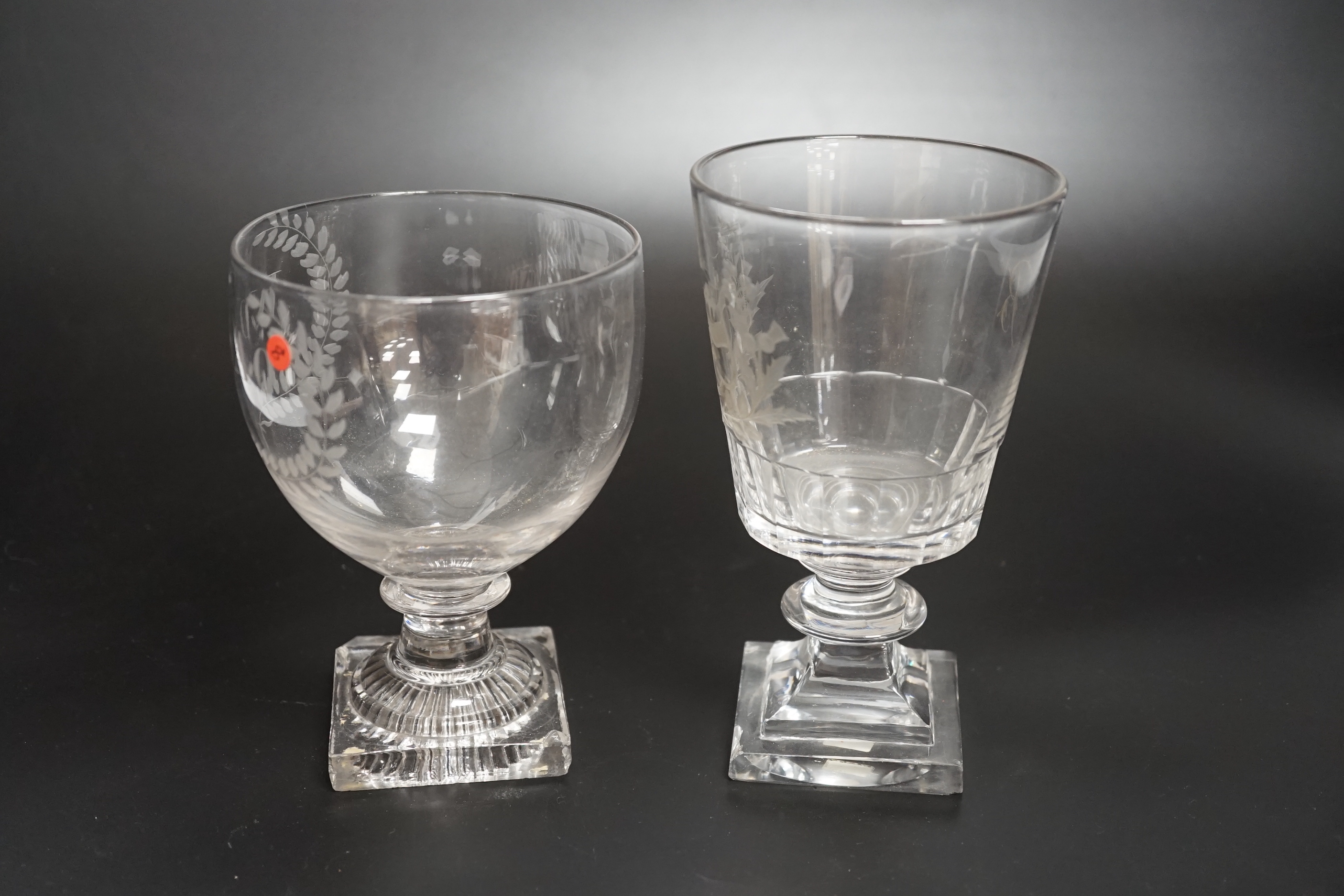 Two rummer style 18th century square-based goblets, both with etched designs, one a coat of arms, both stems with flattened knobs and cut glass square bases, one with ‘lemon squeezer’ pontil, highest 15.5cm